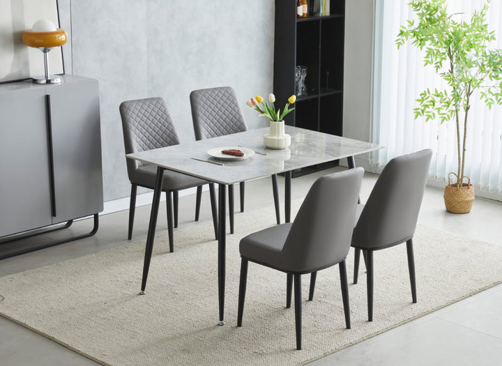A set of dining furniture featuring a grey ceramic table with black legs and four grey leather chairs with black metal legs.