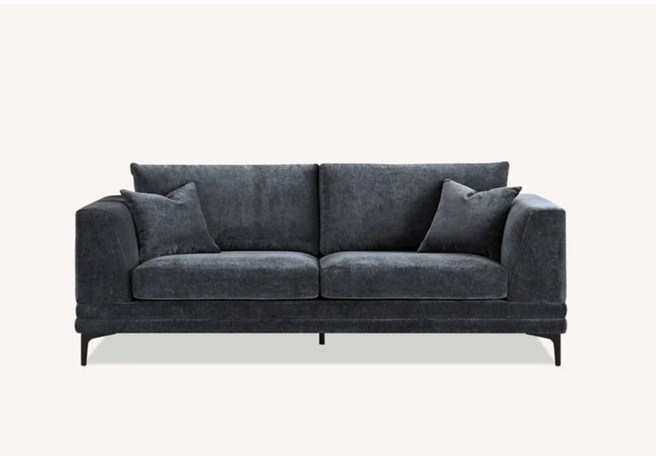 Modern dark grey velvet sofa with square arms, plush cushions, and matching throw pillows on black metal legs