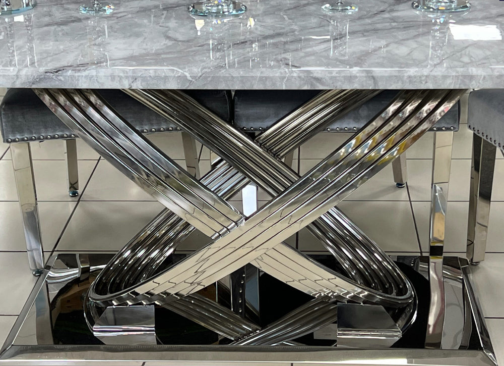 A grey marble dining table with a chrome base, surrounded by chairs with grey upholstery, set on a white tiled floor.