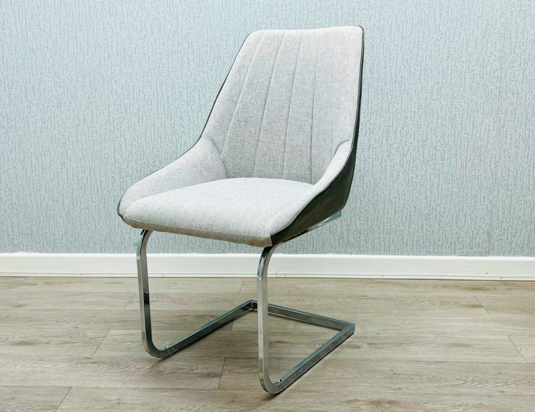 A gray fabric dining chair with a metal frame, pictured against a plain wall on a wooden floor.