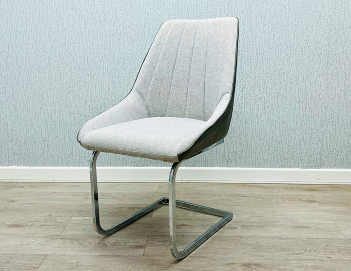 A gray fabric dining chair with a metal frame, pictured against a plain wall on a wooden floor.