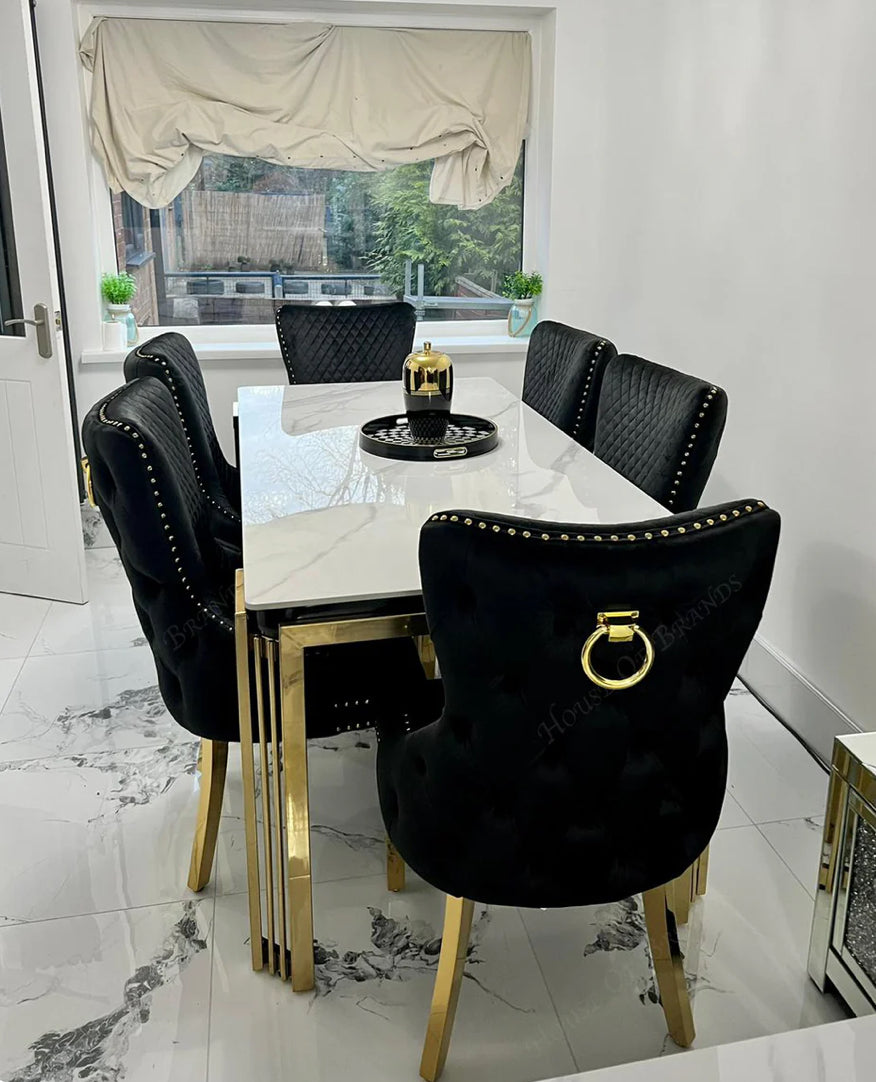 a luxury dining table with white marble top ang gold color leg with six seat black and color chair