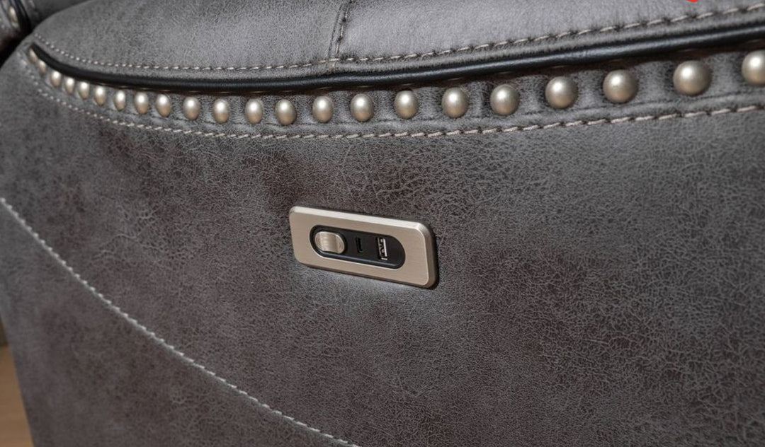 Close-up of grey leather reclining sofa with built-in USB charging port and nailhead trim detailing