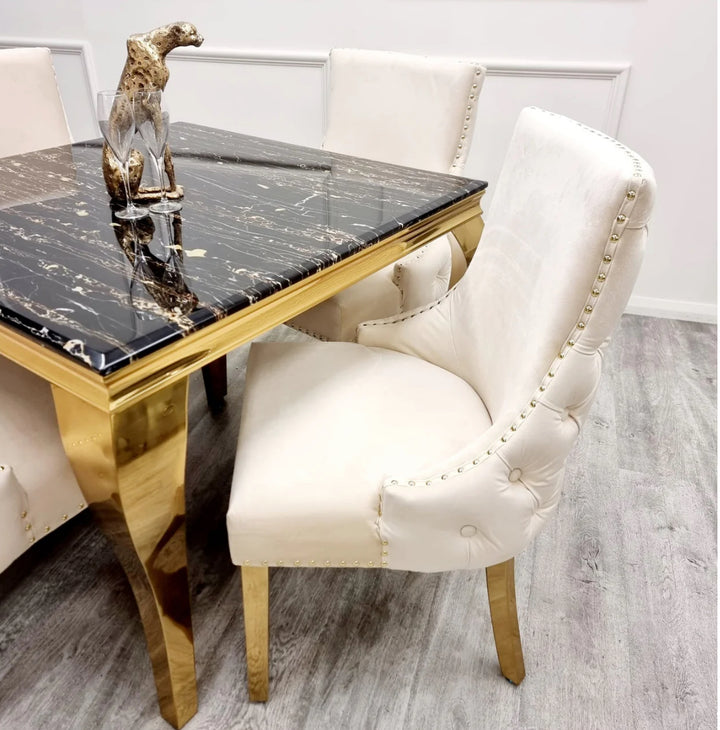 Two Kensington cream dining chairs with gold legs and deep buttoned back design, black marble table with golden leg