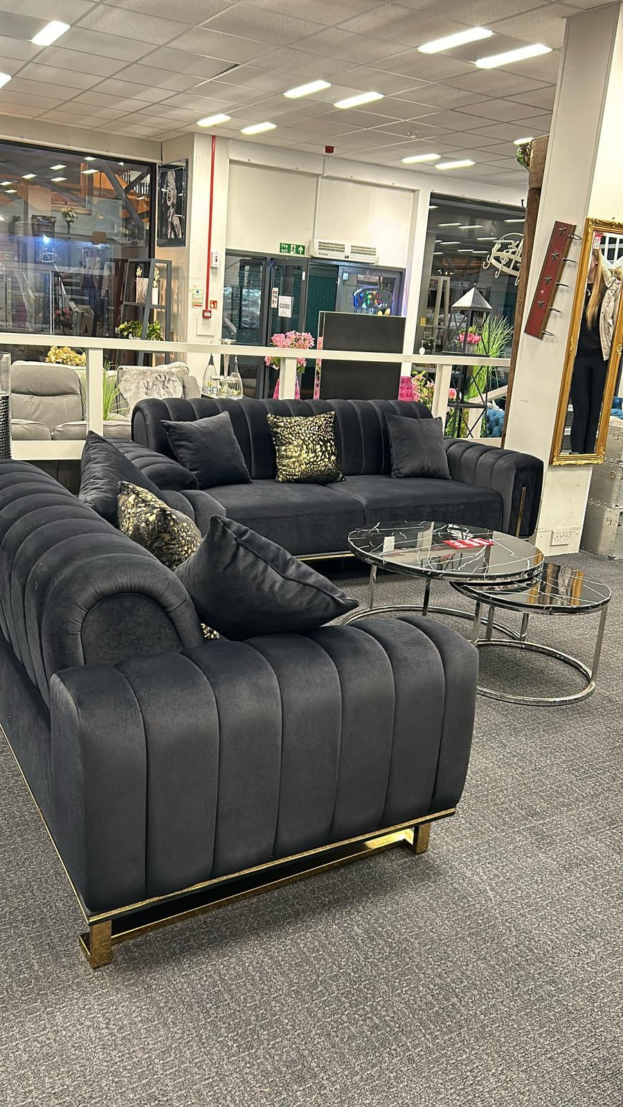A set of gray sofas, including a 3-seater and a 2-seater, with a Chesterfield design, displayed in a showroom.