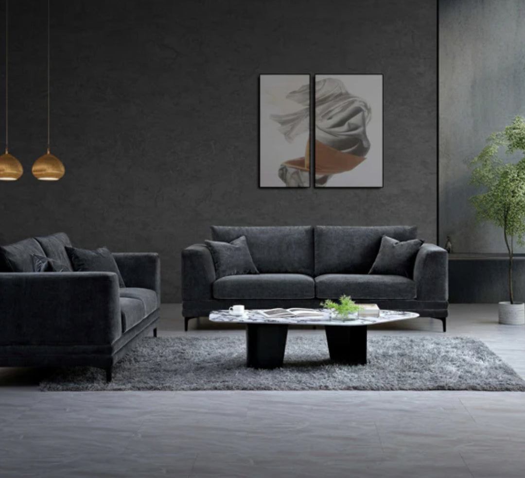 Modern living room with matching dark grey velvet sofas, low marble coffee table, and grey area rug in a minimalist interior