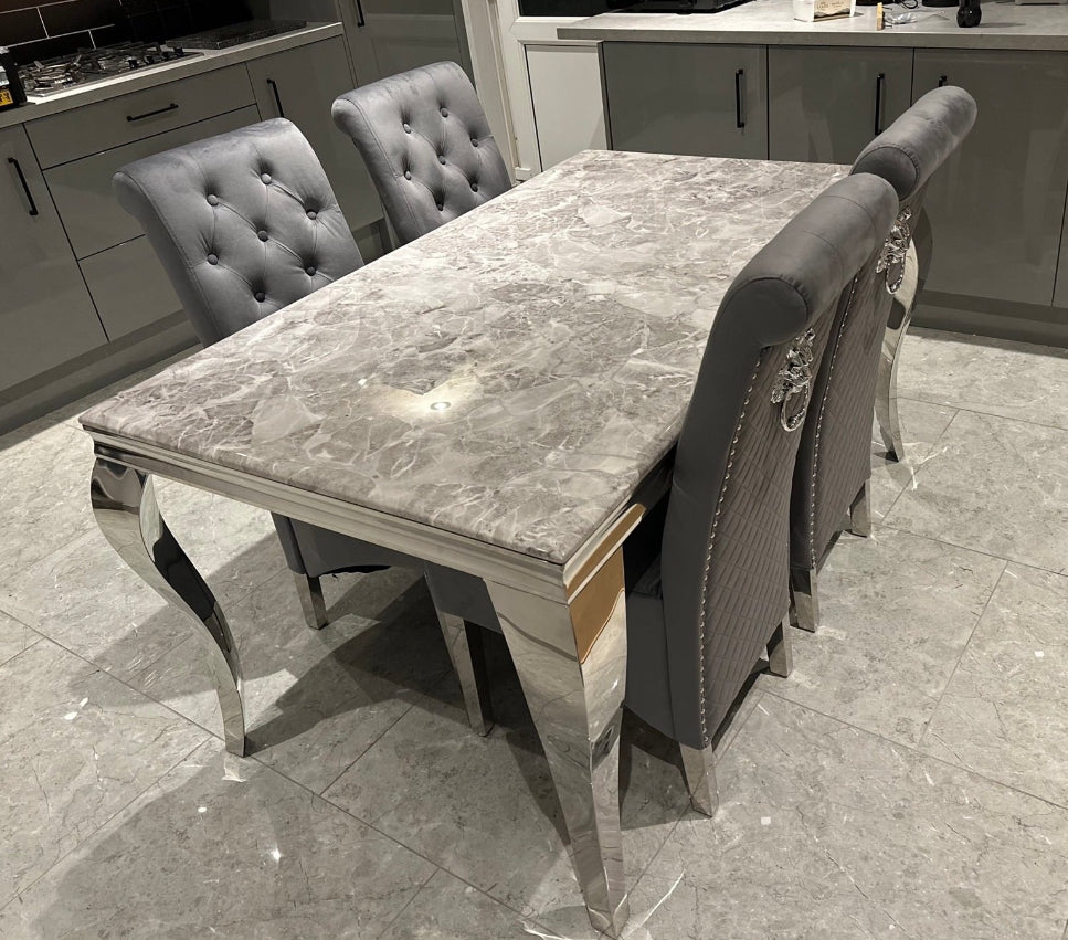 A square marble dining table in a light grey color with four dark grey upholstered chairs with a chrome leg and a lion knocker on a shiny floor.