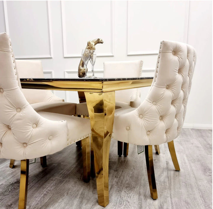 Two Kensington cream dining chairs with gold legs and deep buttoned back design, black marble table with golden leg