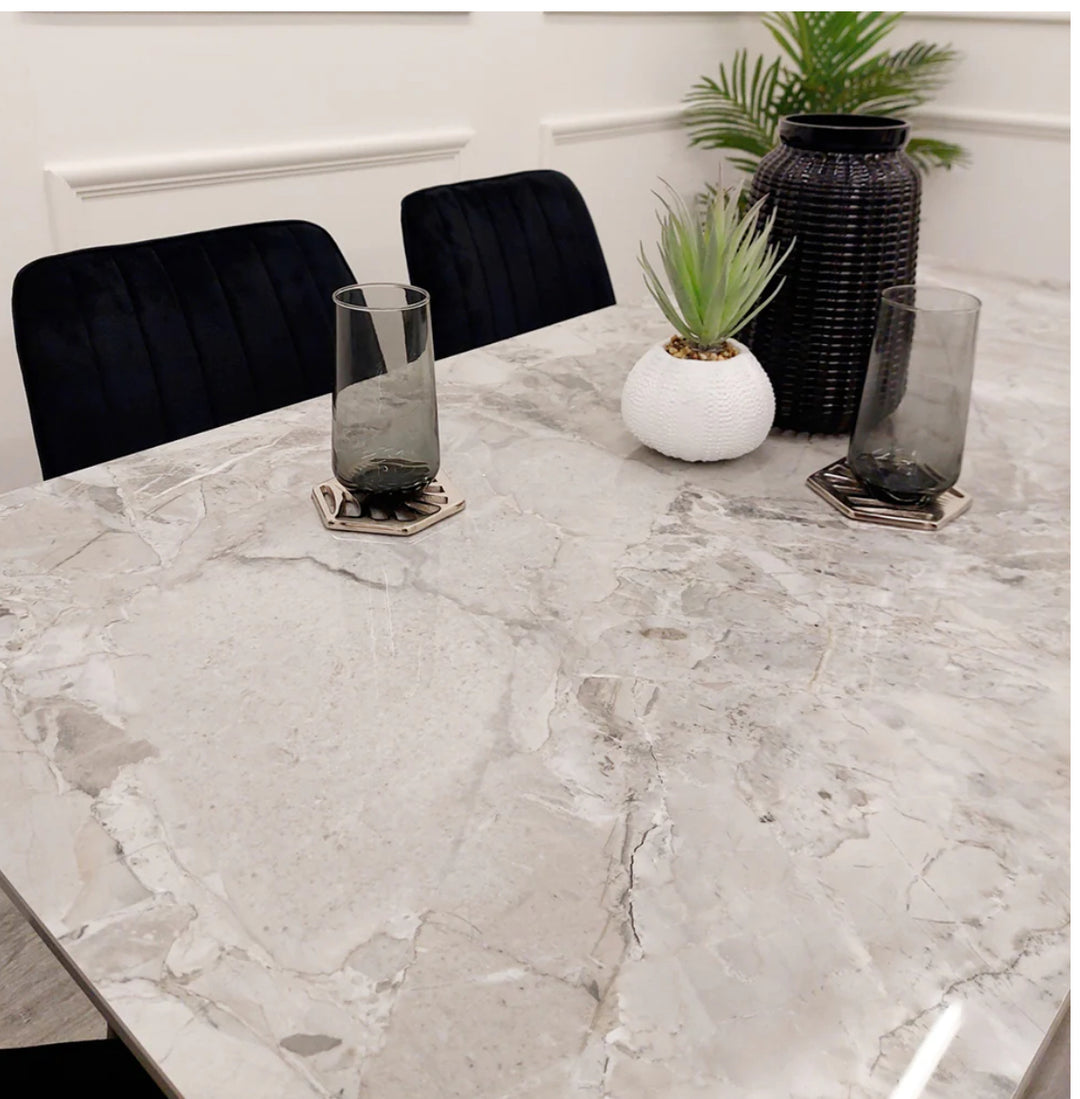 A black dining table with a grey sintered stone top and black tapered legs.