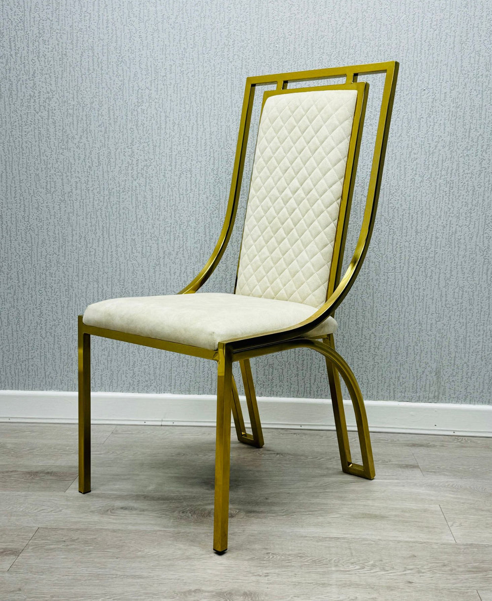 single  modern high back dining chairs with quilted cream upholstery and gold stainless steel frame, shown on light wood flooring against textured wallpaper