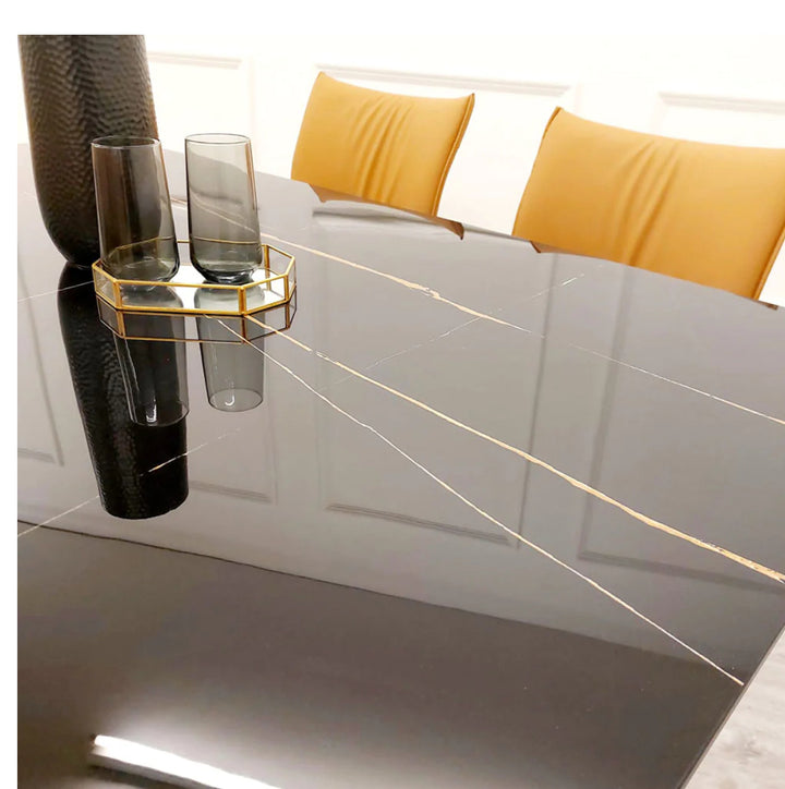 Glossy black marble dining table with gold veining detail, styled with mustard chairs and modern black and gold decor accents