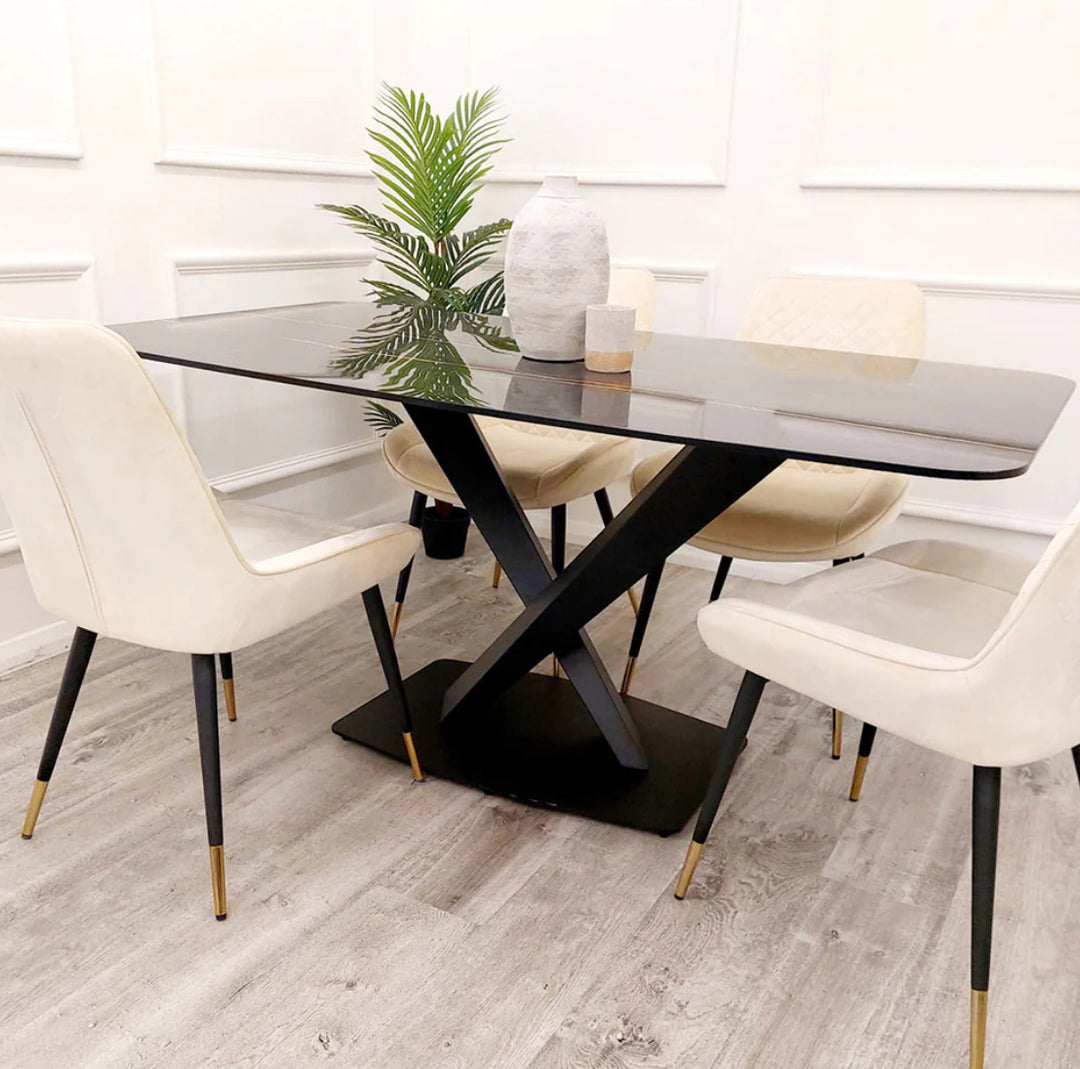 Modern dining set with glossy black rectangular table and cream velvet chairs featuring black and gold legs, placed on light wood flooring