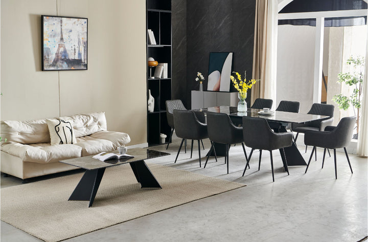 An extendable dining table in black with six dark grey leather chairs, set in a room with minimalist decor.