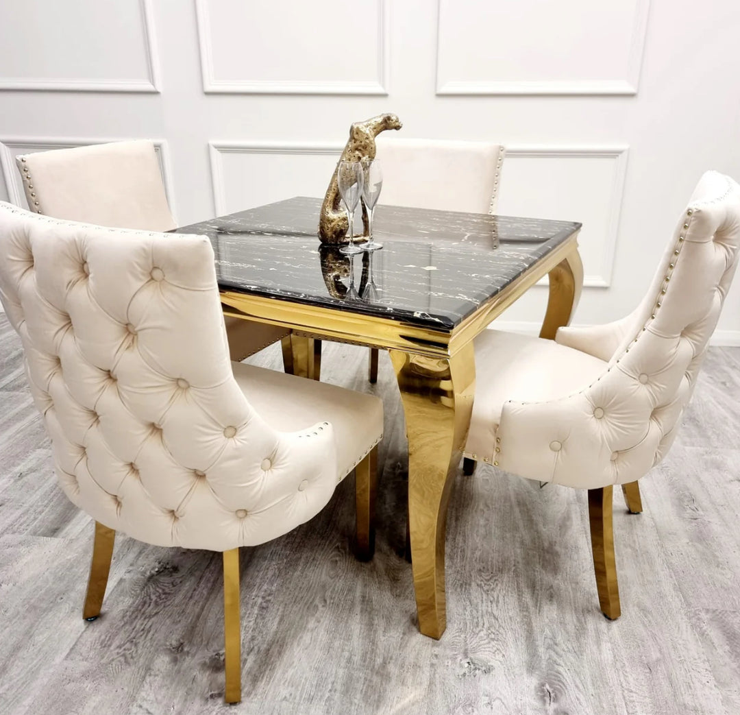 Two Kensington cream dining chairs with gold legs and deep buttoned back design, black marble table with golden leg