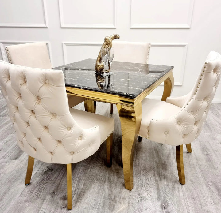 Two Kensington cream dining chairs with gold legs and deep buttoned back design, black marble table with golden leg
