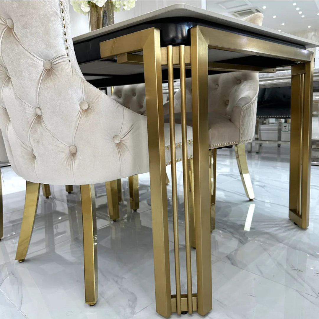 A white marble dining table with gold legs, accompanied by beige upholstered dining chairs with gold accents.