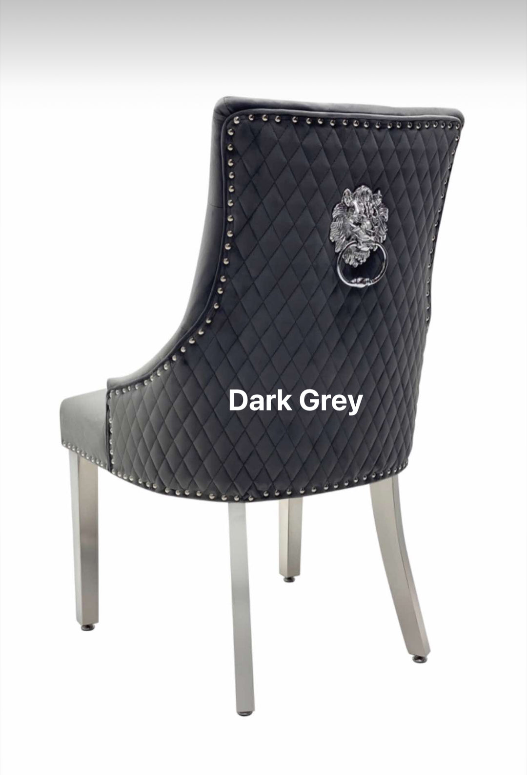 A beige upholstered dining chair with a dark grey lion knocker on the backrest and chrome-colored legs.