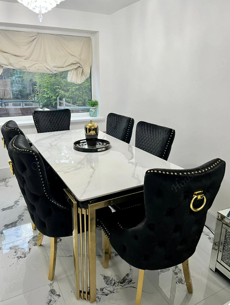 a luxury dining table with white marble top ang gold color leg with six seat black and color chair