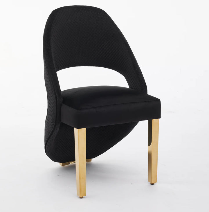 A black plush velvet dining chair with gold-colored metallic legs.