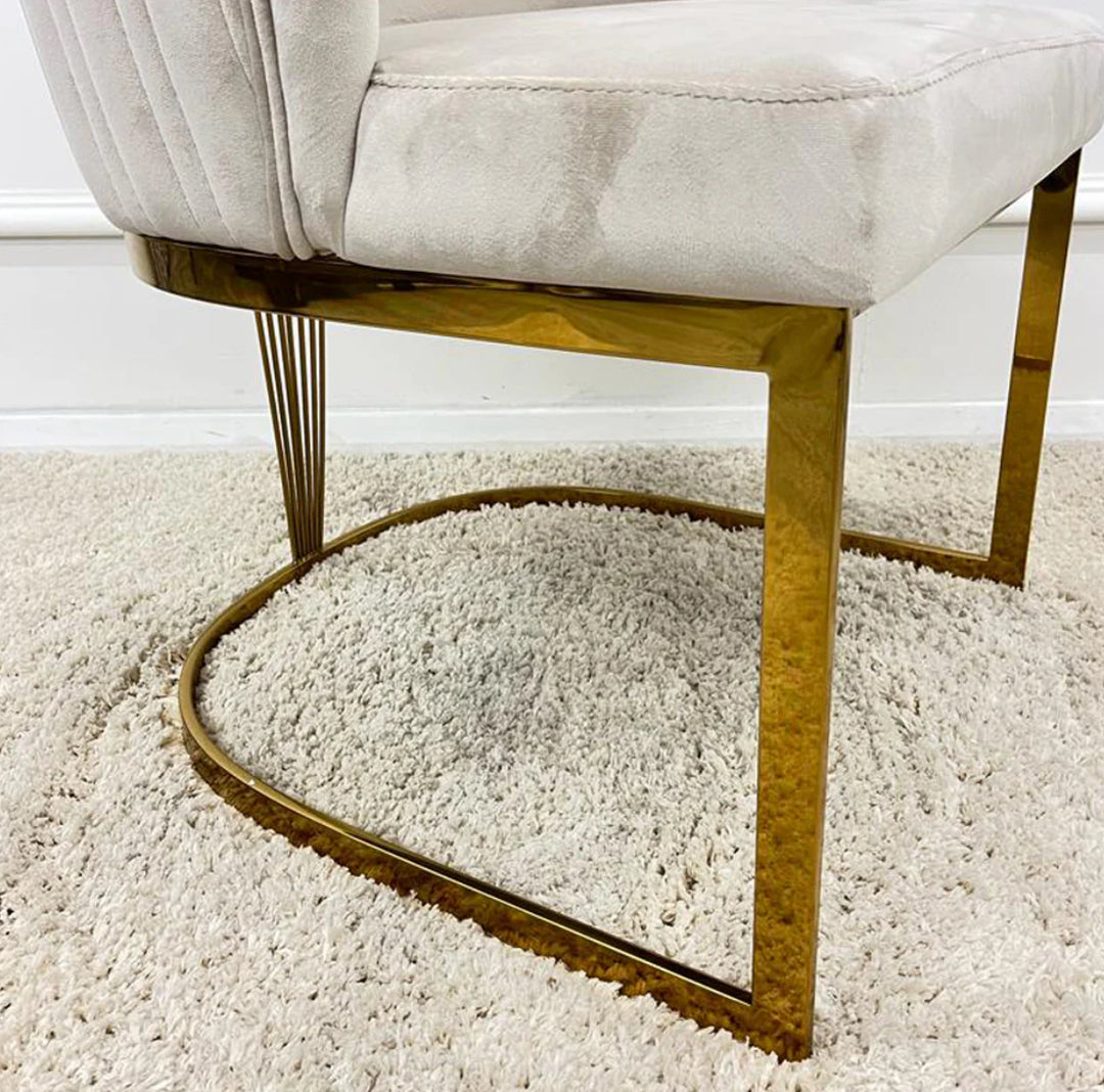 Close-up of modern white velvet dining chair with gold metal legs and U-shaped base on cream shaggy rug