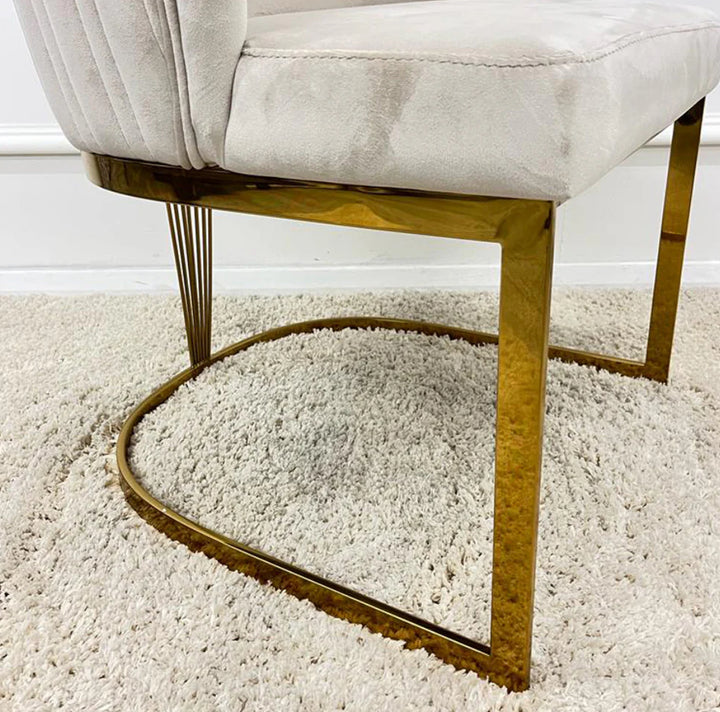 Close-up of modern white velvet dining chair with gold metal legs and U-shaped base on cream shaggy rug