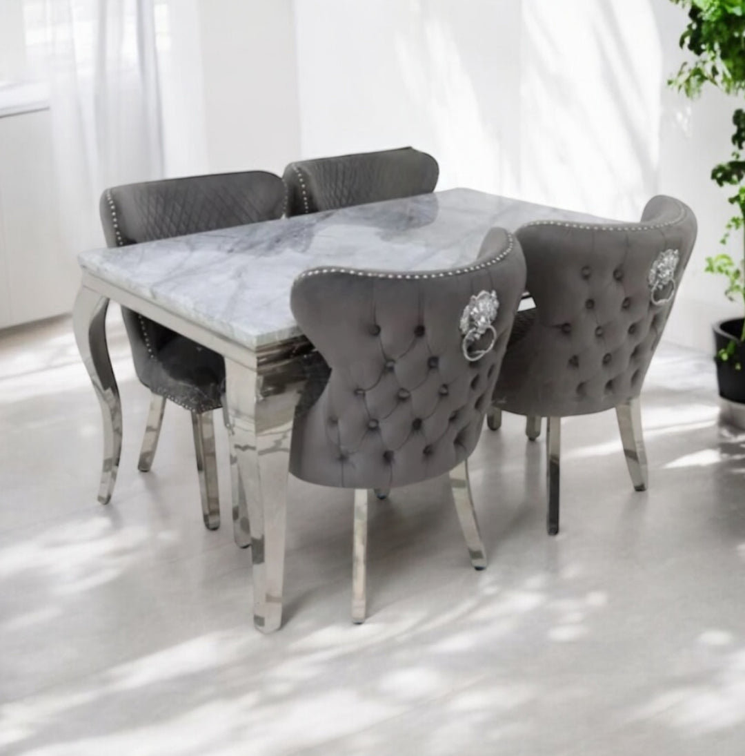 A square marble dining table with dark grey upholstered chairs with tufted backrests and lion knocker designs on the headrests.
