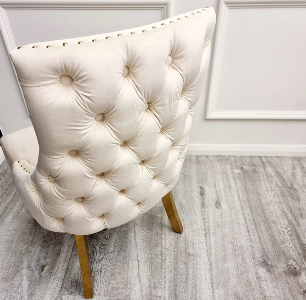 Two Kensington cream dining chairs with gold legs and deep buttoned back design, one showing the side profile and the other showing the back detail.