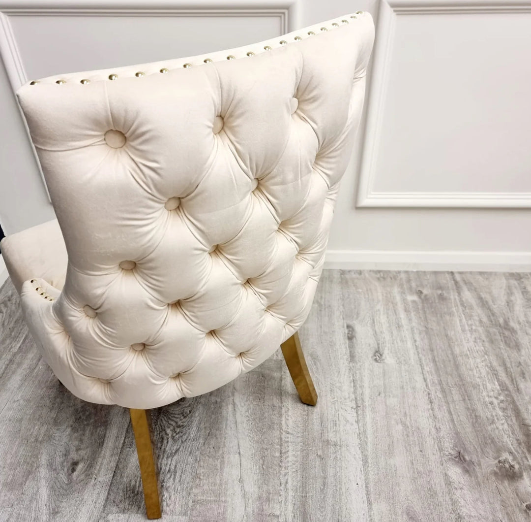 Two Kensington cream dining chairs with gold legs and deep buttoned back design, one showing the side profile and the other showing the back detail.