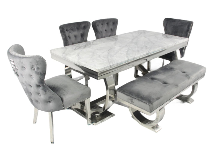 A marble dining table with a rectangular shape and four dark grey leather chairs with upholstered seats and backrests, featuring a polished metallic frame.