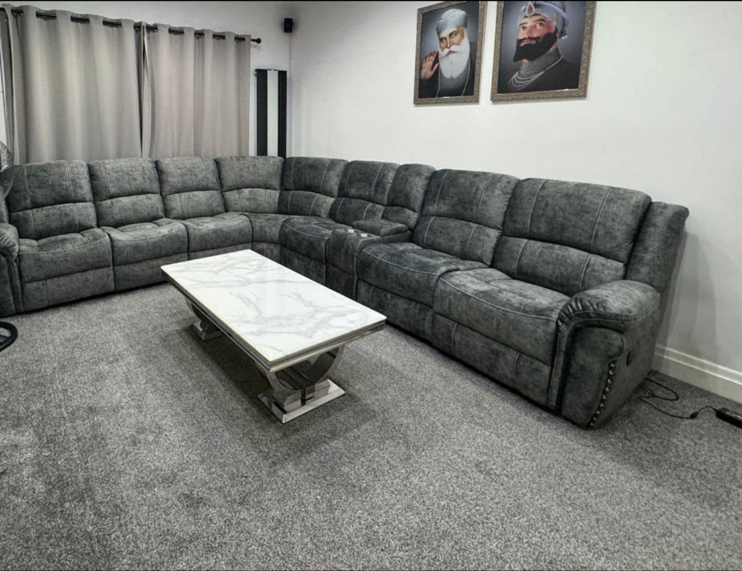 Modern grey L-shaped reclining sofa set with marble-top coffee table on grey carpet in a contemporary living room