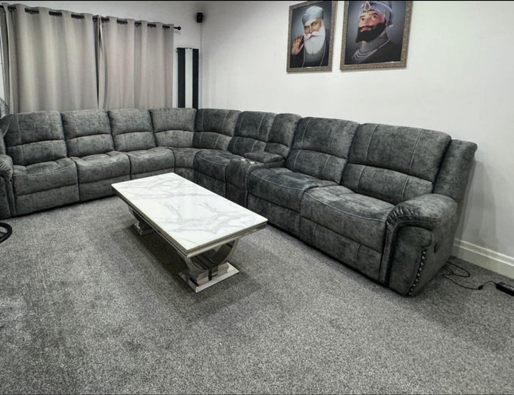 Modern grey L-shaped reclining sofa set with marble-top coffee table on grey carpet in a contemporary living room