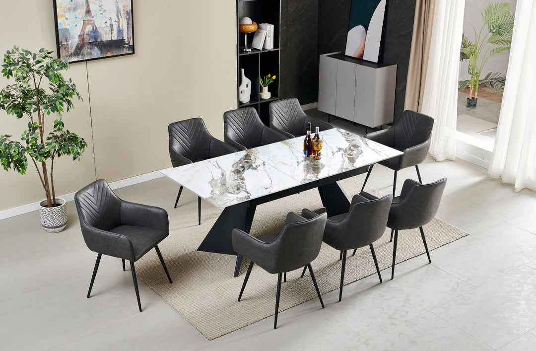 An extendable white dining table with dark grey leather chairs arranged around it, set in a modern living space.