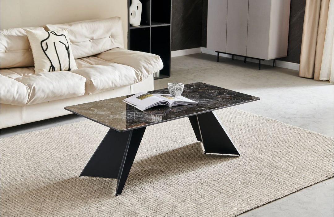 A black coffee table with a marble-like tabletop, positioned on a rug with a book and a cup on top, set against a cozy living room background.