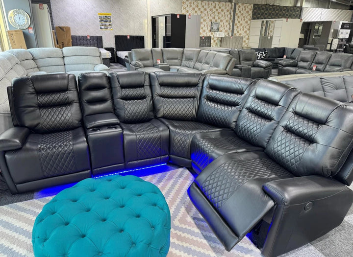 Black leather sectional sofa with quilted design in a showroom setting.