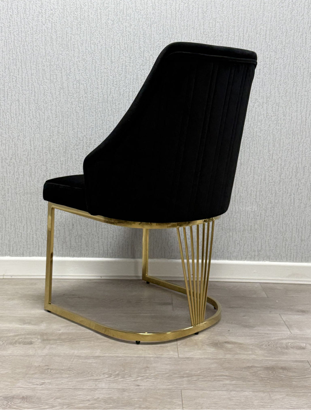 A grey upholstered dining chair with a gold metal frame and a cushioned seat and backrest.