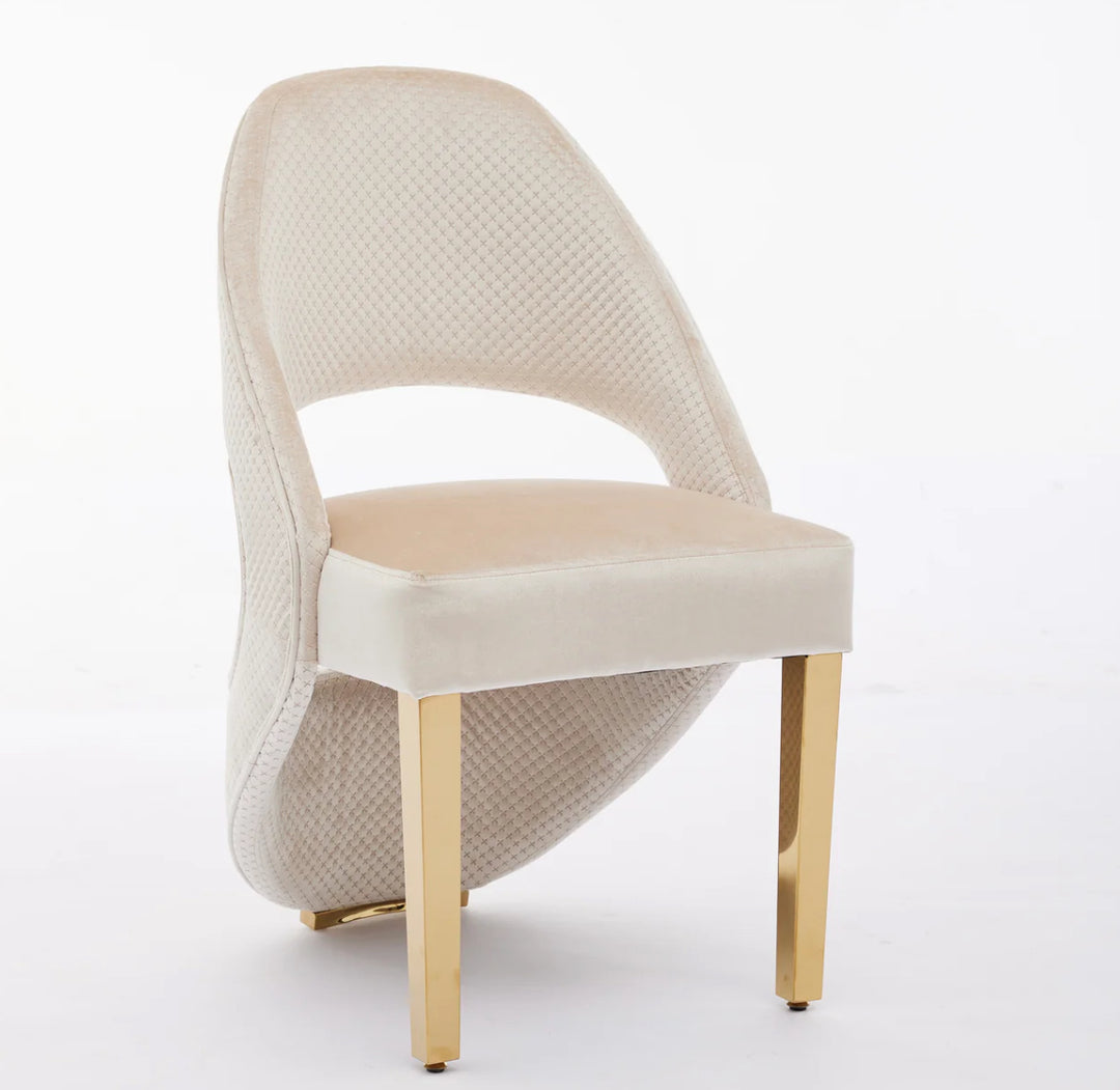 A plush velvet dining chair with a cream backrest and gold seat, featuring gold legs.