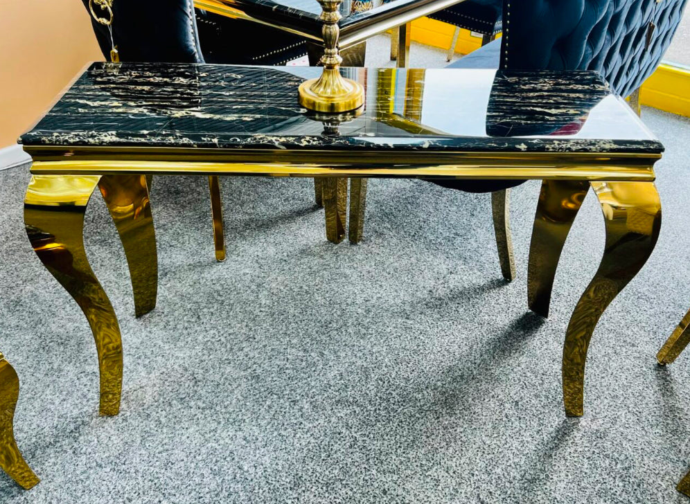 A black and gold marble console table with gold-colored legs, displayed in a room setting.