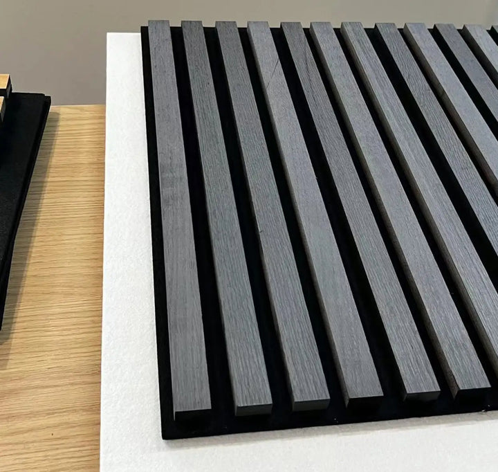 A set of wood effect veneer wall panels in an ash grey color, installed on a wall with a table and chairs in front of them.