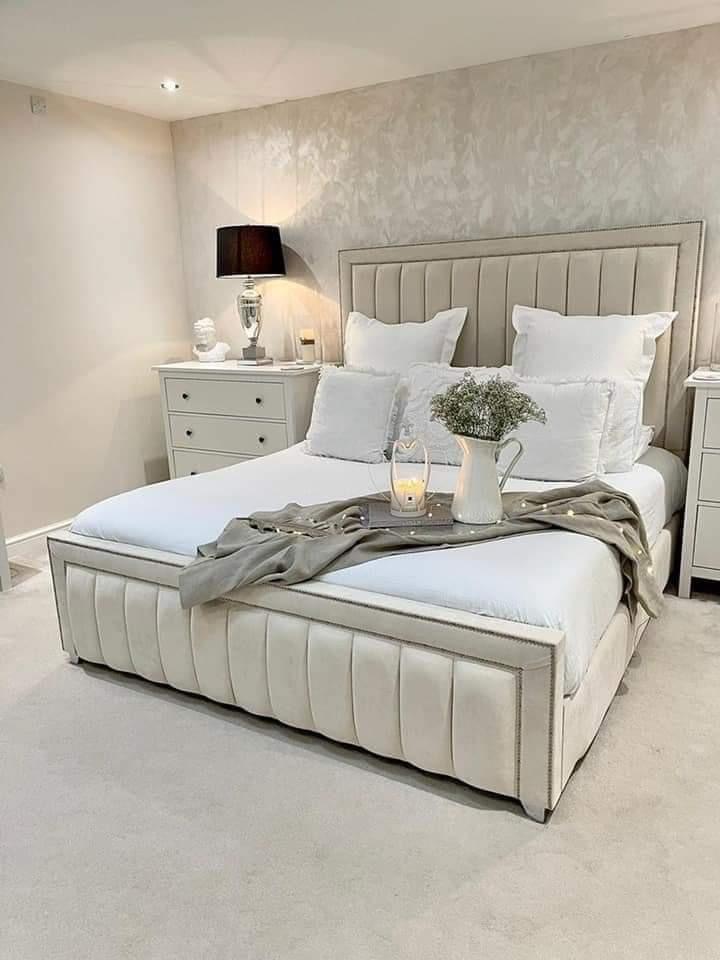 A luxurious white Monaco bed with a high headboard, neatly made with white bedding, positioned in a well-lit, tidy bedroom.