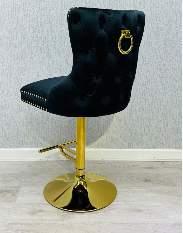 A black colored bar stool with gold accents, featuring a tufted backrest and a lion knocker on the back.
