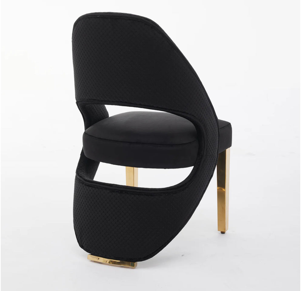 A black plush velvet dining chair with chrome legs, viewed from a  side angle against a white background.