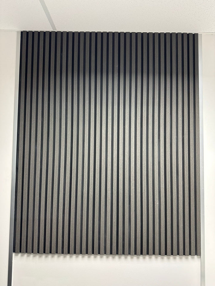 A set of wood effect veneer wall panels in an ash grey color, installed on a wall with a table and chairs in front of them.