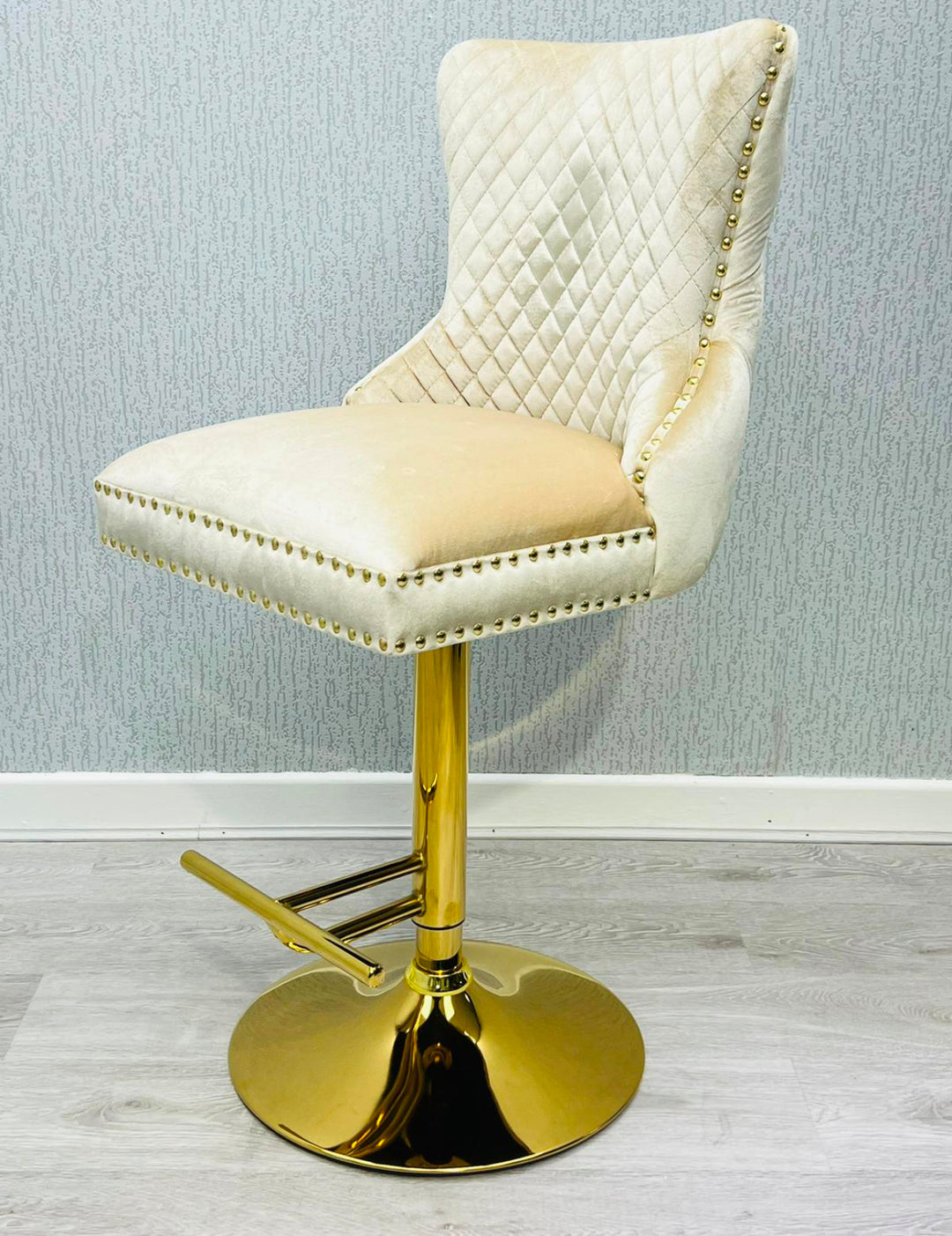 A black colored bar stool with gold accents, featuring a tufted backrest and a ring knocker on the back.