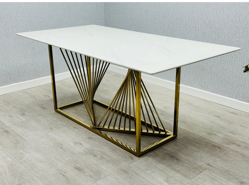 Modern white marble dining table with geometric gold stainless steel base, featuring a minimalist rectangular design on light wood flooring