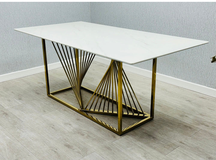 Modern white marble dining table with geometric gold stainless steel base, featuring a minimalist rectangular design on light wood flooring