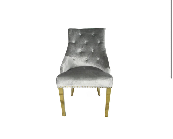 A silver dining chair with gold accents and upholstered backrest, seated on a wooden leg.