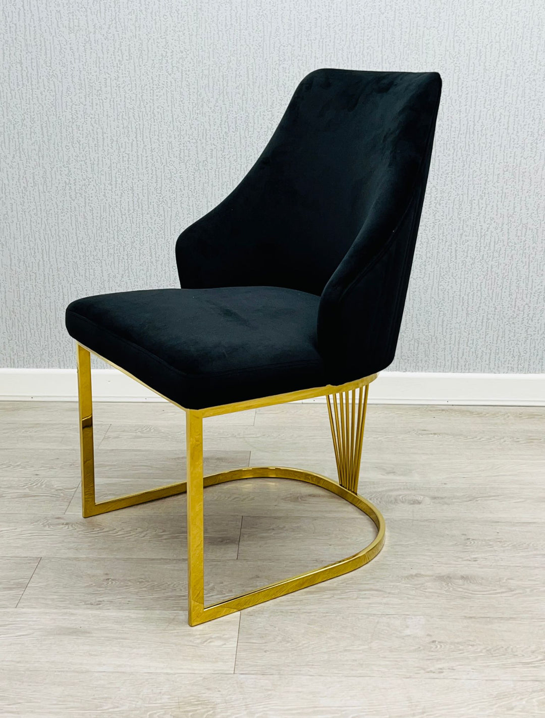 A black chair with a gold frame, positioned against a neutral background.