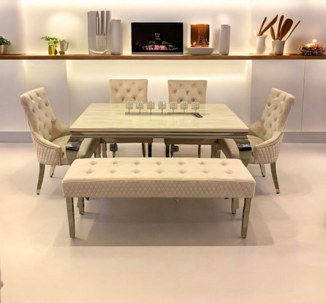 A cream-colored marble dining table with four chairs and a matching bench, set in a modern dining room with minimalist decor.