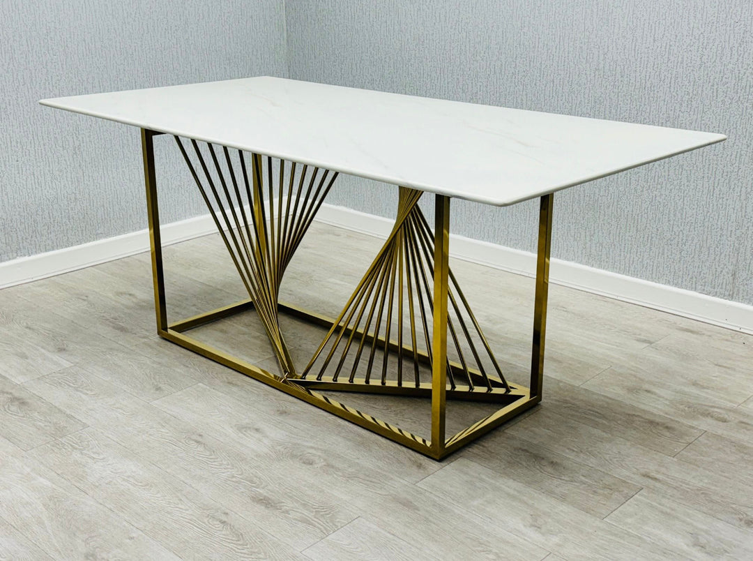 Modern white marble dining table with geometric gold stainless steel base, featuring a minimalist rectangular design on light wood flooring