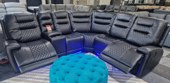 Black leather sectional sofa with a blue ottoman in a showroom setting